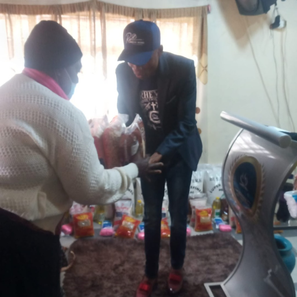 Apostle Keith handing food to lady in white sweater